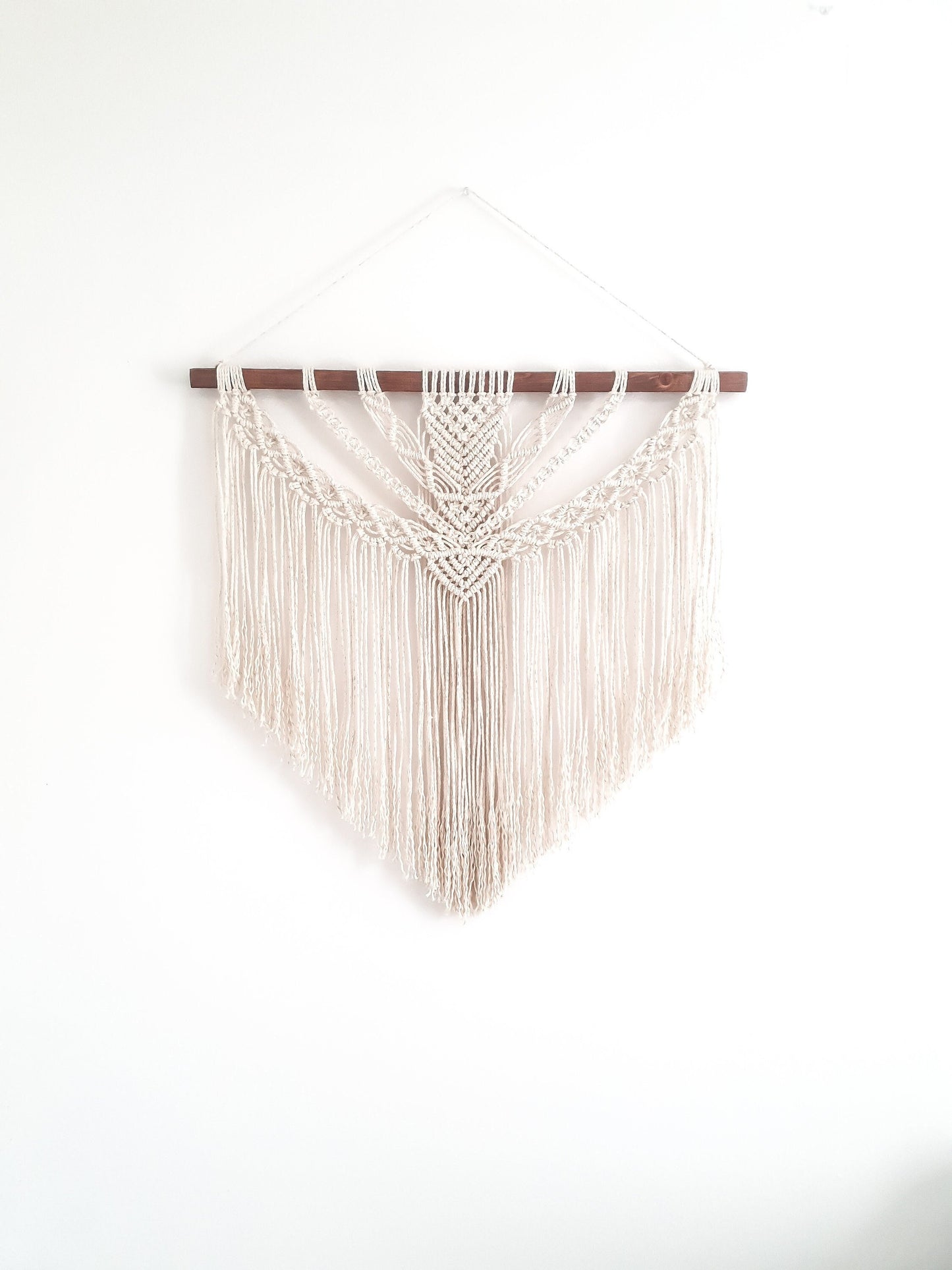 beige (off white) fiber art on a piece of dark walnut stained wood.