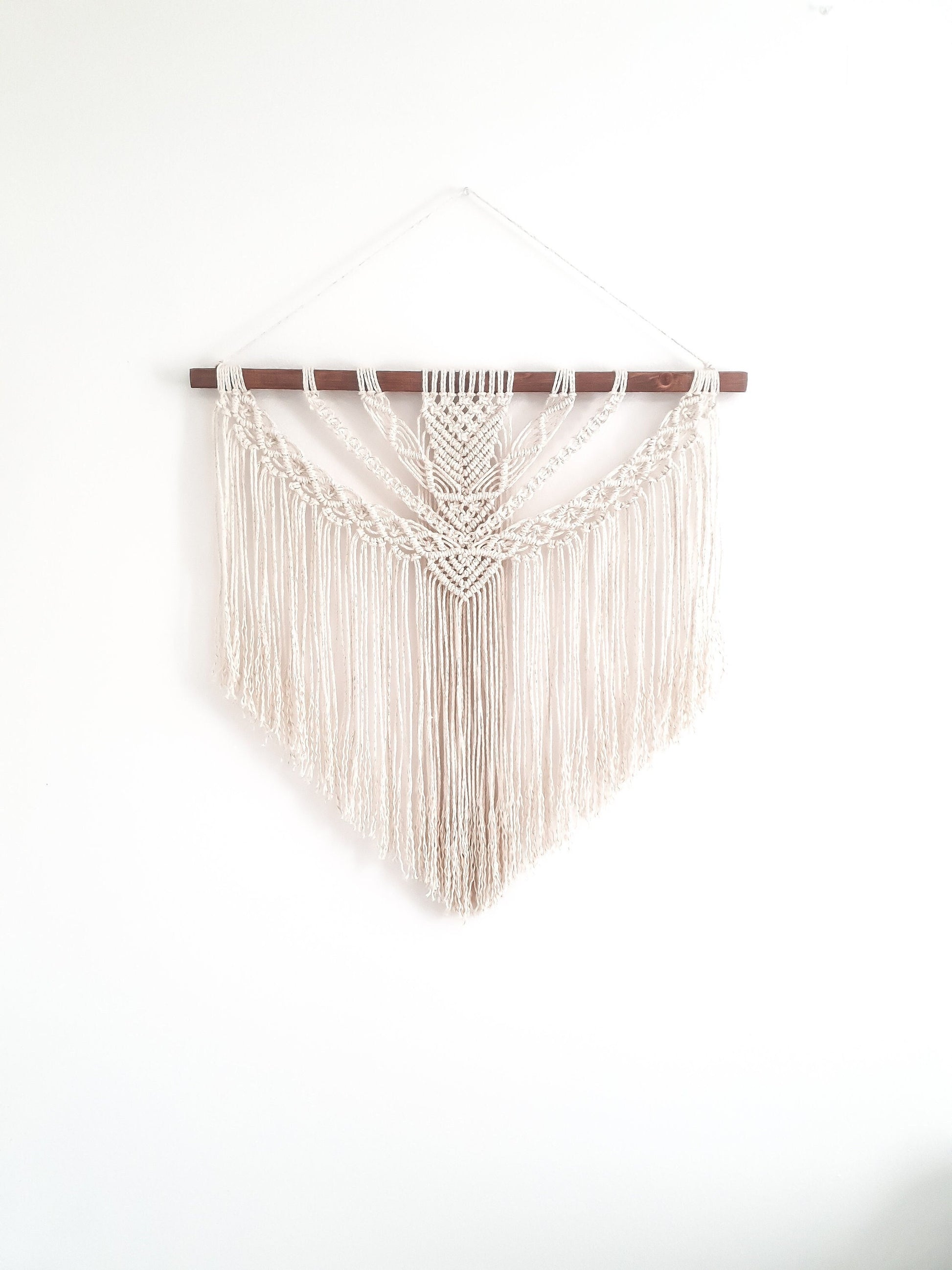 beige (off white) fiber art on a piece of dark walnut stained wood.
